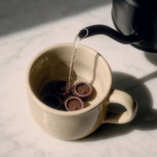 Kakao-Drops in einer Tasse, heißes Wasser wird aufgegossen